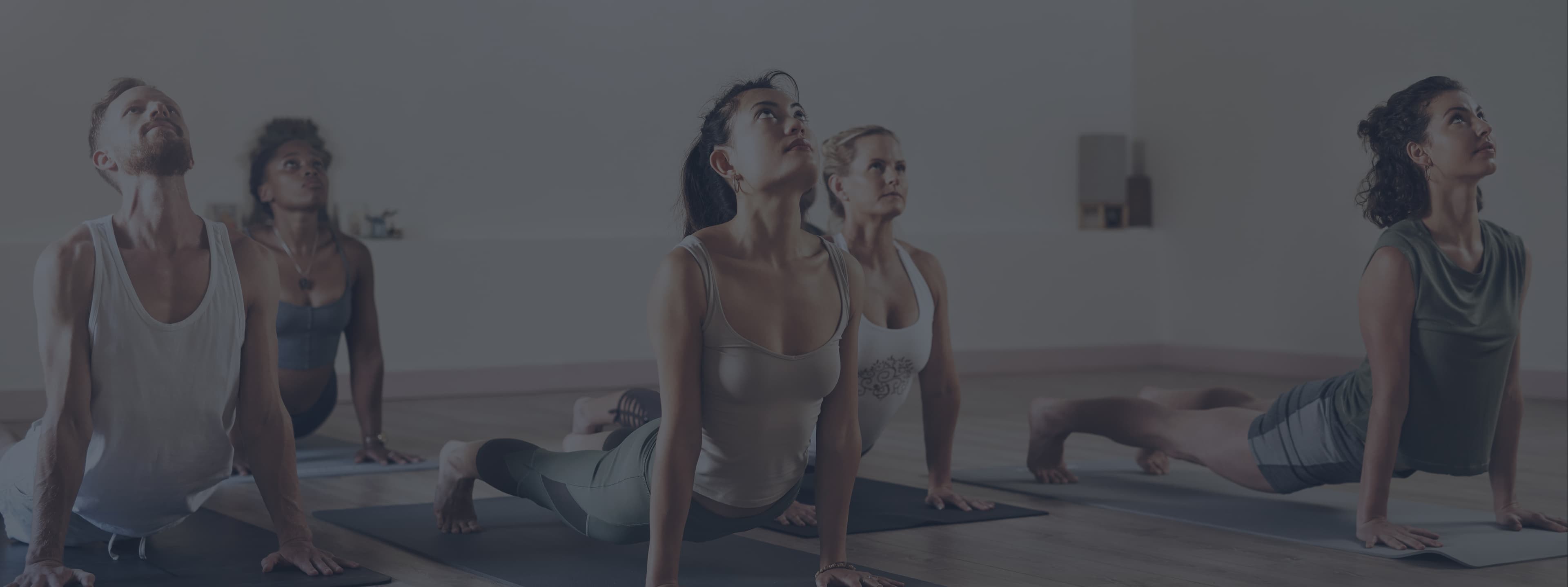 Groupe de personnes pratiquant le yoga dans une salle moderne et lumineuse, ambiance zen et détendue